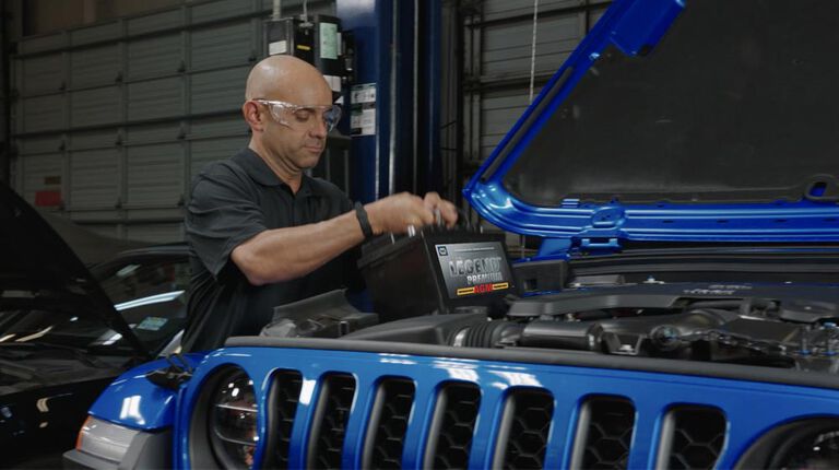 Kal Tire team member putting new battery in vehicle