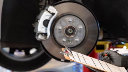 Kal Tire team member with clip board checking brakes