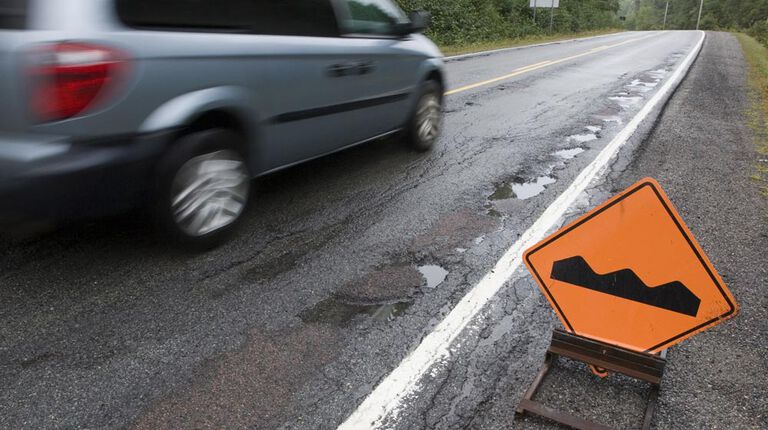 Vehicle on rough road going by bump in road sign